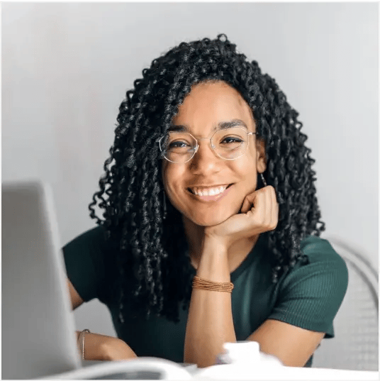 woman with curly hair smiling behind laptop