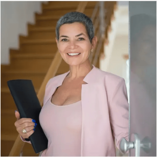 woman in pink blazer holding laptop smiling