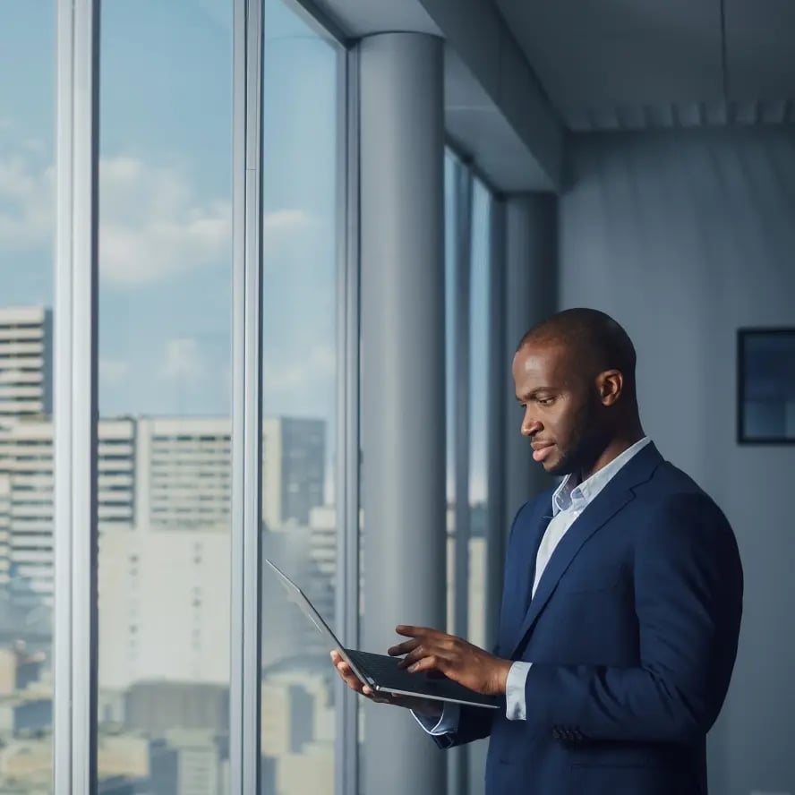 man looking at laptop by window